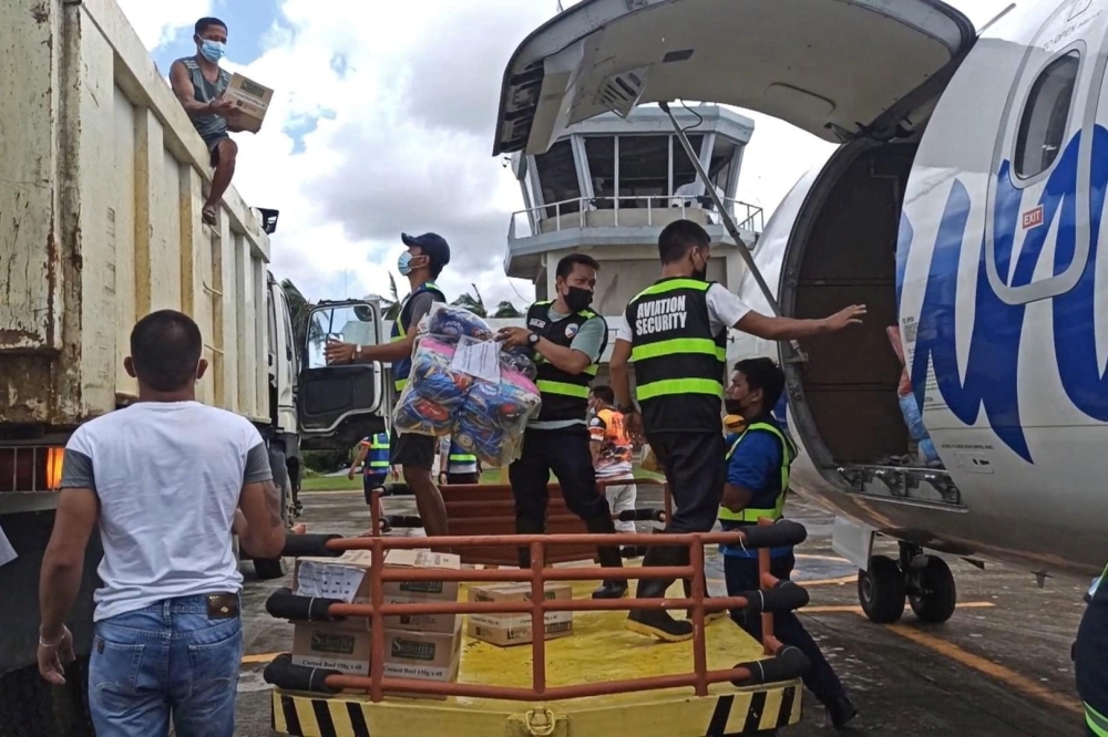 Aviation personnel assist in unloading packs of relief goods for victims of typhoon Rai, in Surigao del Norte province, Philippines, December 18, 2021. Philippine Coast Guard/Handout via Reuters