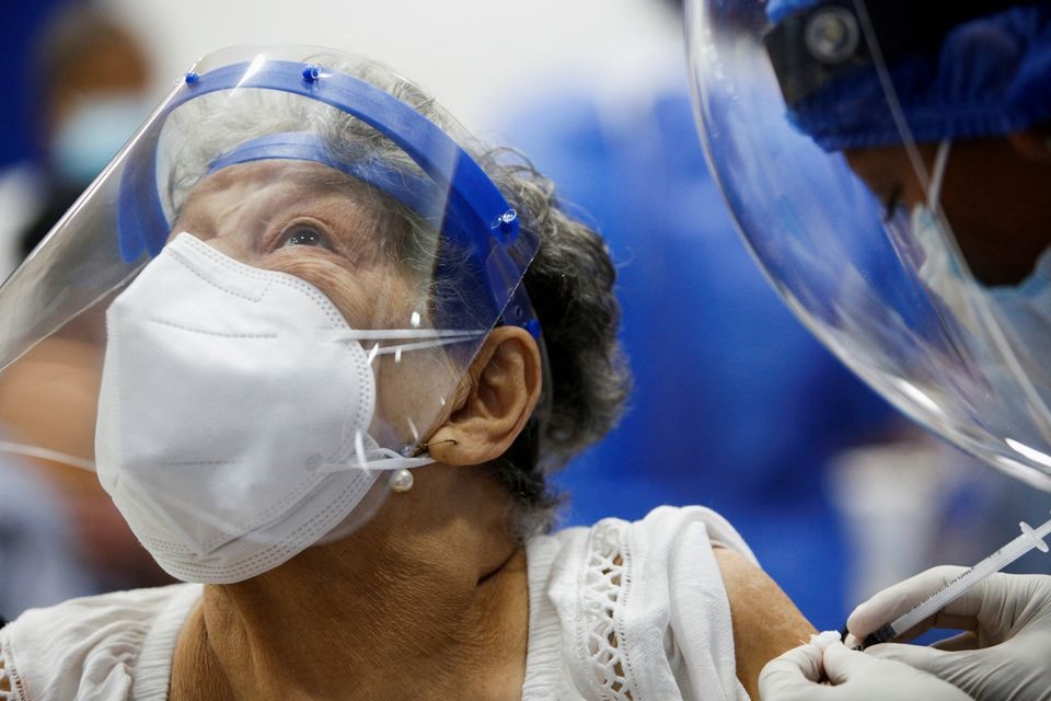 A woman reacts as she receives the first dose of China's Sinovac Biotech vaccine against the coronavirus disease (COVID-19), during a mass vaccination program for the elderly, at the Bolivarian Technology Institute in Guayaquil, Ecuador April 15, 2021. REUTERS/Santiago Arcos


