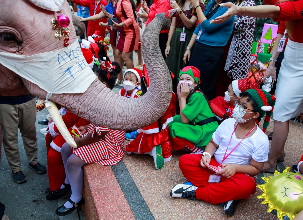 Students receive gifts from an elephant during a the visit of five elephants in Santa Claus costumes with giant face masks delivering hand sanitizers and promoting a 