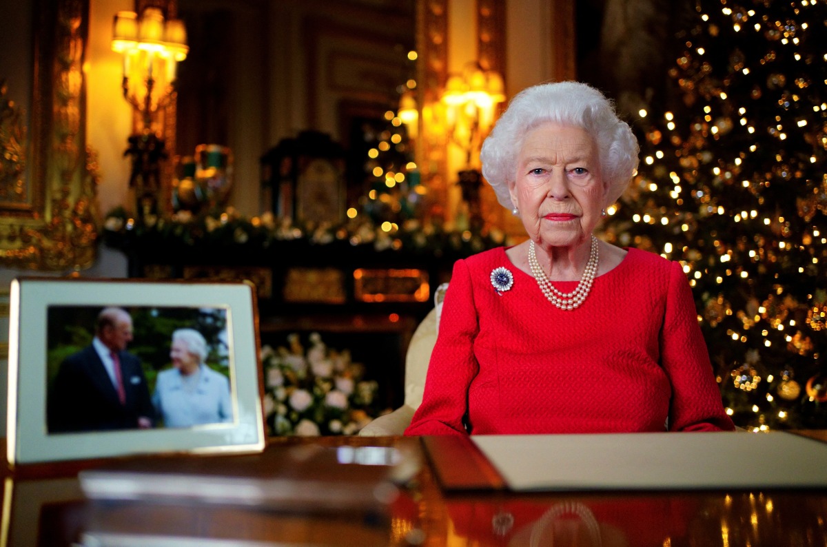 Britain's Queen Elizabeth records her annual Christmas broadcast in the White Drawing Room in Windsor Castle, next to a photograph of the queen and the Duke of Edinburgh, in Windsor, Britain, December 23, 2021. Victoria Jones/Pool via REUTERS
