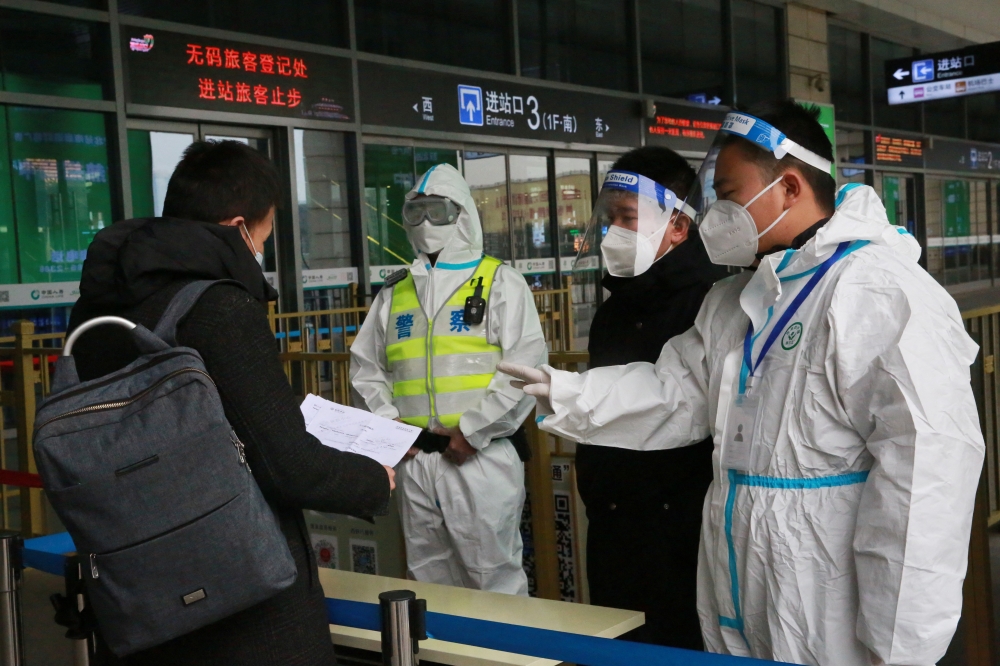 Police and staff members wearing protective gear inspect the documents of a traveller at an entrance to a railway station, in Xian, Shaanxi province, China December 23, 2021. China Daily via Reuters 