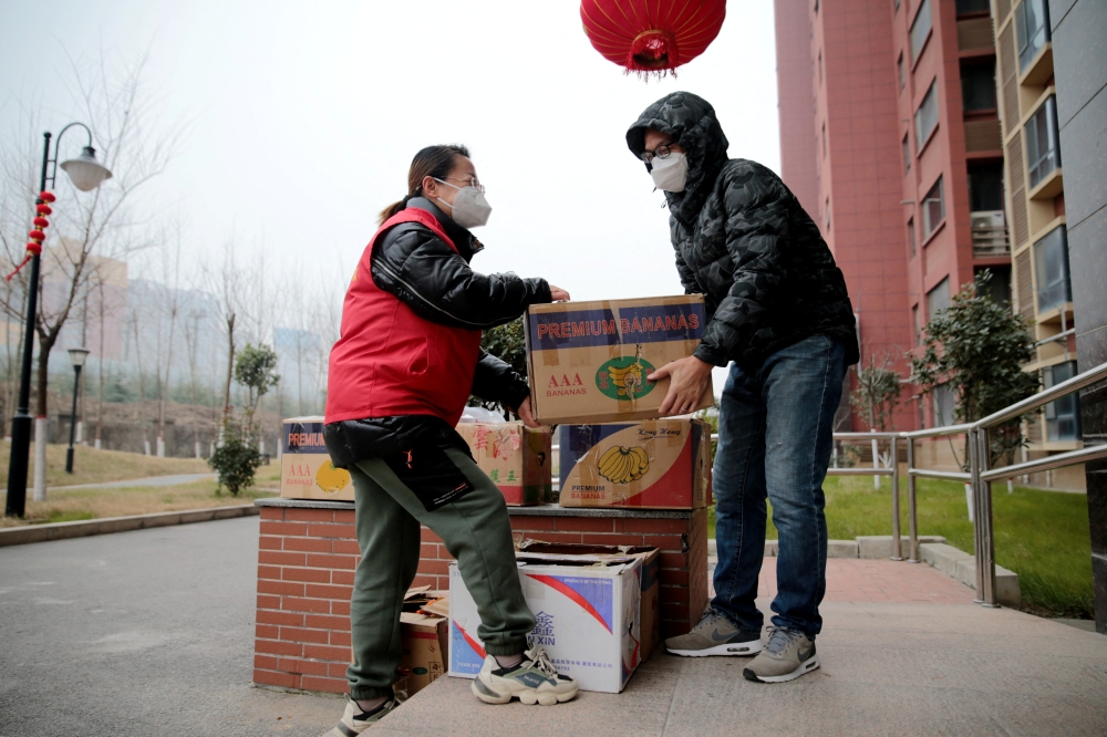 A resident receives free food supplies provided by local government at a residential compound under lockdown, following the coronavirus disease (COVID-19) outbreak in Xian, Shaanxi province, China January 5, 2022. cnsphoto via REUTERS
