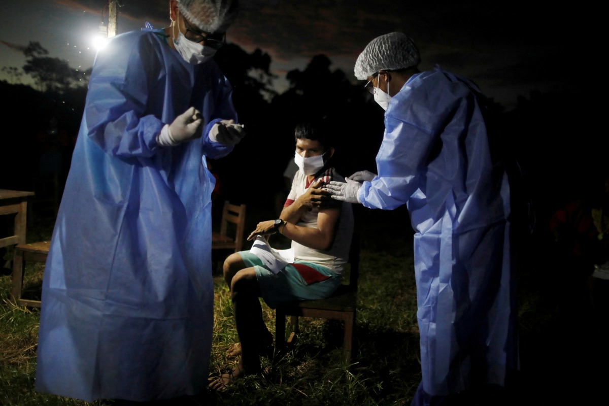 FILE PHOTO: A man is administered a vaccine for the coronavirus disease (COVID-19) at night during an outreach by healthcare workers who traveled by river into the Amazon rainforest to educate people from the indigenous Urarina community about the disease and offer medical care, in San Marcos, Peru October 11, 2021. Picture taken October 11, 2021. REUTERS/Sebastian Castaneda/File Photo
