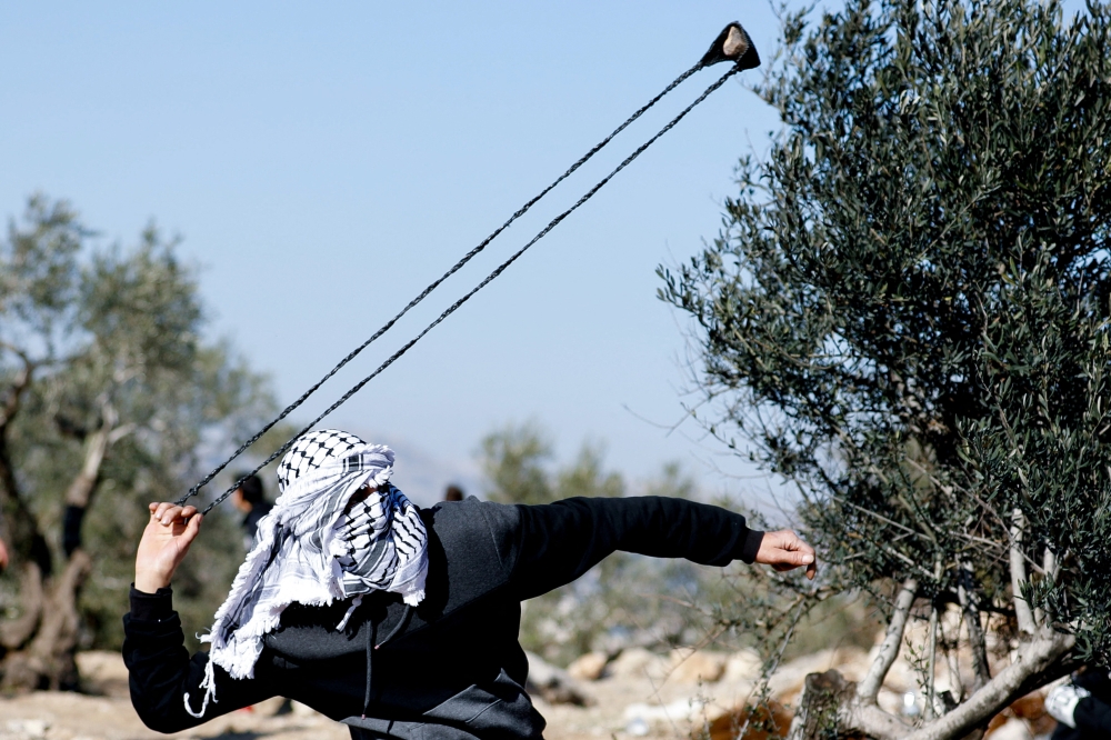 A Palestinian demonstrator uses a sling during a protest against Israeli settlements, West Bank, January 7, 2022. REUTERS.