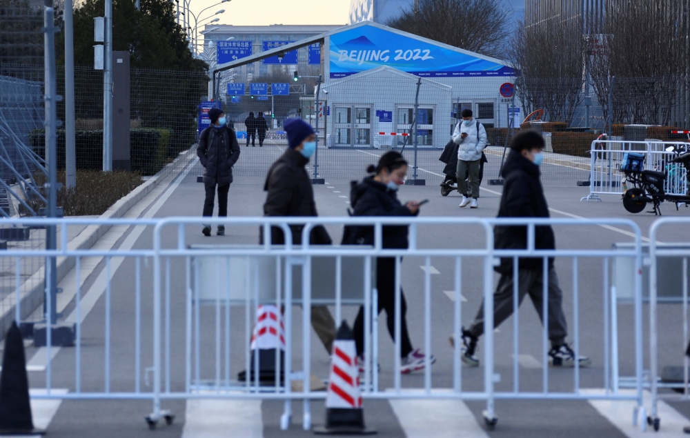People walk behind a barrier outside a closed loop area designed to prevent the spread of the coronavirus disease (COVID-19) ahead of the Beijing 2022 Winter Olympics in Beijing, China, January 11, 2022. (REUTERS/Fabrizio Bensch)
