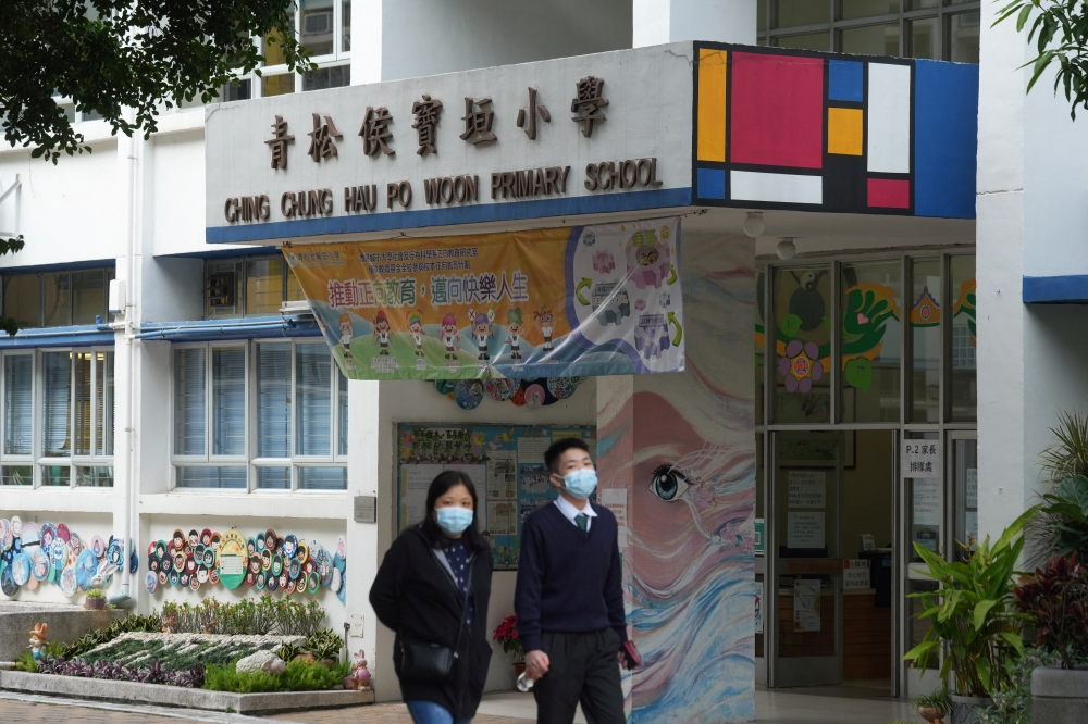 People wearing face masks walk outside a primary school, following coronavirus disease (COVID-19) infections in Hong Kong, China January 11, 2022. REUTERS/Lam Yik