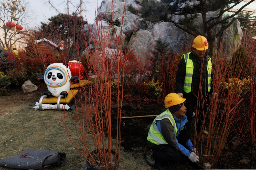 Workers plant bushes in the ground near the mascot of the Beijing 2022 Winter Olympics in Beijing, China, January 14, 2022. REUTERS/Thomas Peter