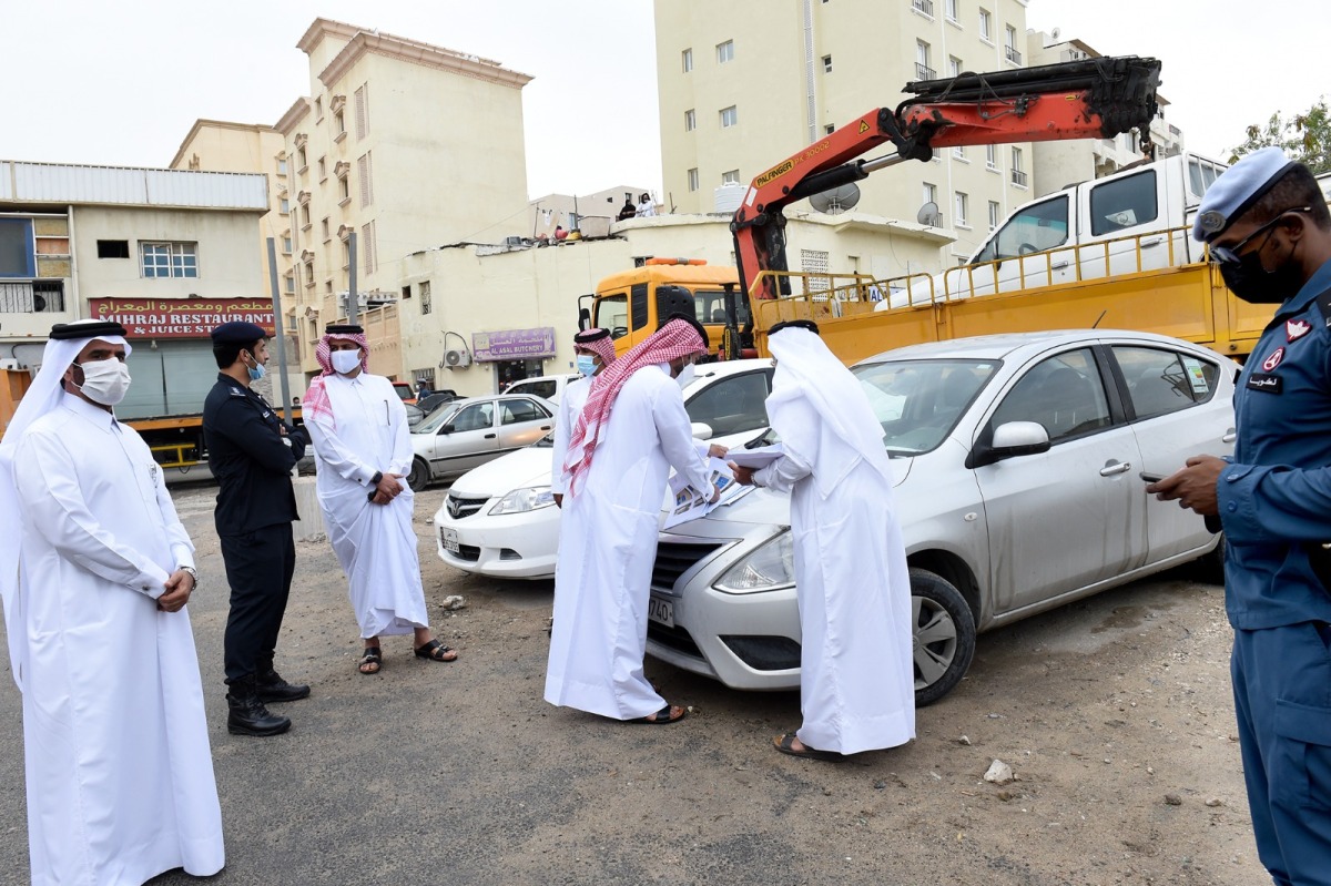 Officials inspect and mark an abandoned car in Doha, yesterday. 