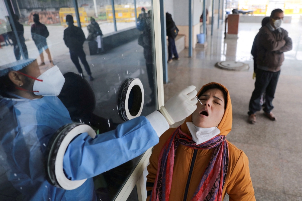 A healthcare worker collects a test swab sample from a woman amidst the spread of the coronavirus disease (COVID-19), at a testing centre inside a hospital in New Delhi, India, January 14, 2022. REUTERS/Anushree Fadnavis/File Photo