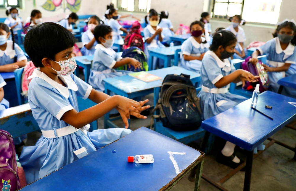 Students apply hand sanitiser while attending a class at the Viqarunnisa Noon School & College after the government has withdrawn restrictions on educational institutions following a decrease in the number of cases of coronavirus disease (COVID-19) in Dhaka, Bangladesh, September 12, 2021. REUTERS/Mohammad Ponir Hossain/File Photo
