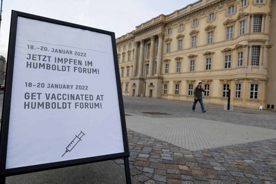 A sign displaying the dates that a pop-up vaccination centre is open is seen, as a person walks outside the coronavirus disease (COVID-19) vaccination centre in the Humboldt Forum, in Berlin, Germany January 19, 2022. REUTERS/Michele Tantussi

