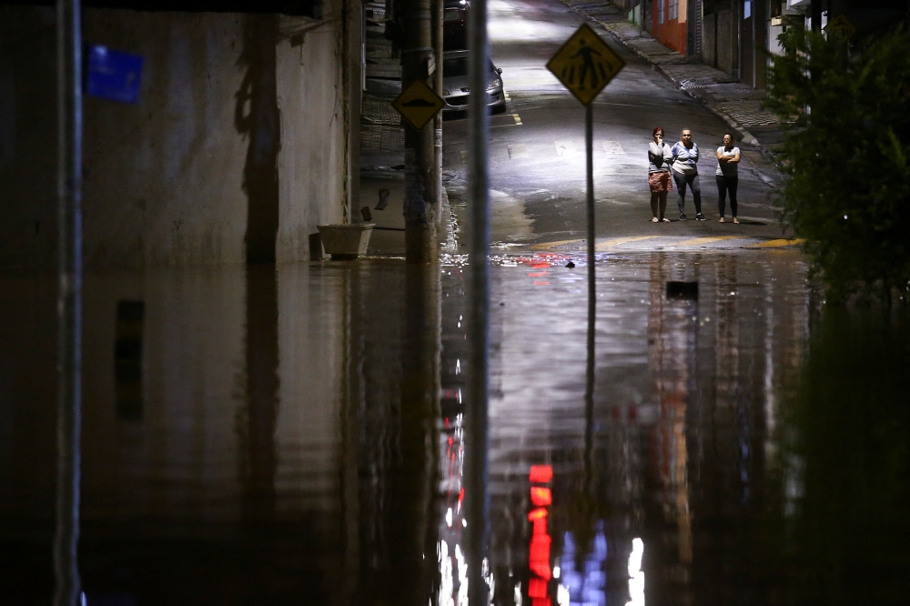 People observe a flooded street after heavy rain in Caieiras, Brazil January 30, 2022. REUTERS/Carla Carniel