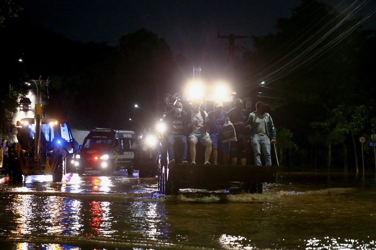 A bulldozer carries people across a flooded street after heavy rains in Caieiras, Brazil January 30, 2022. REUTERS/Carla Carniel
