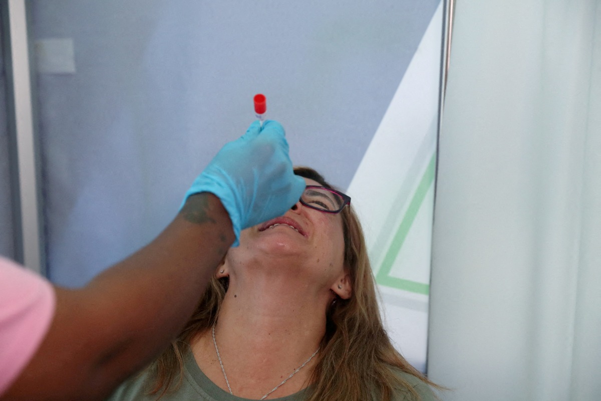 FILE PHOTO: A healthcare worker collects a swab for a PCR test against the coronavirus disease (COVID-19) at O.R. Tambo International Airport in Johannesburg, South Africa, November 26, 2021. REUTERS/ Sumaya Hisham/File Photo
