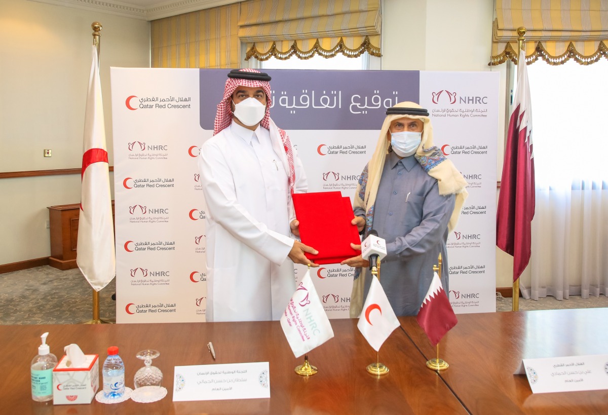 Ali bin Hassan Al Hammadi, Secretary-General of QRCS, and Sultan bin Hassan Al Jamali, Secretary General of NHRC, exchanging document after signing the agreement.