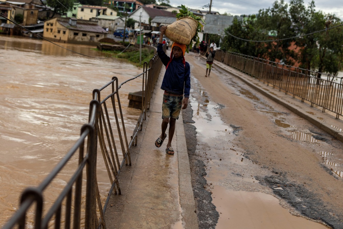 A boy carries vegetables in a flooded area, as Cyclone Batsirai sweeps inland, in Fianarantsoa, Madagascar, February 6, 2022. REUTERS/Alkis Konstantinidis
