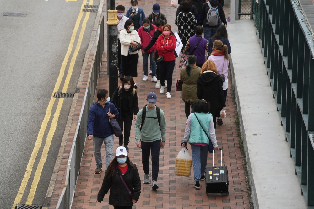 Pedestrians wearing face masks following the coronavirus disease (COVID-19) outbreak walk on a street in Hong Kong, China February 8, 2022. REUTERS/Lam Yik