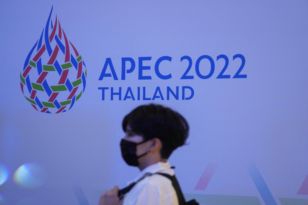  A woman passes by the logo of the APEC Summit 2022 at a department store in Bangkok, Thailand, November 18, 2021. Reuters/Athit Perawongmetha/File Photo