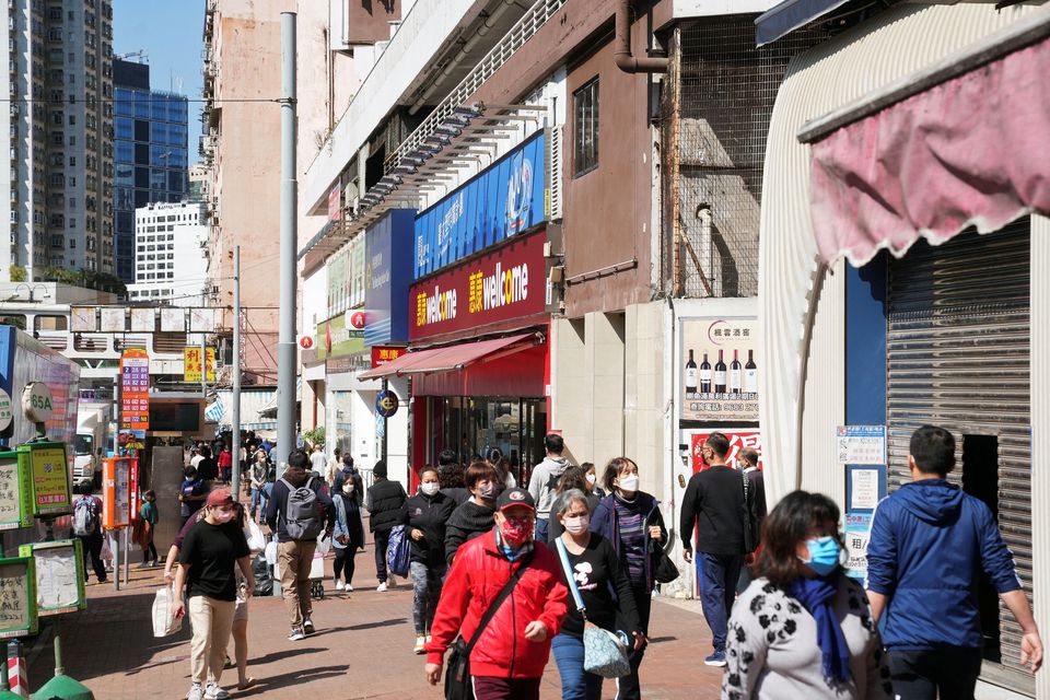 Pedestrians wearing face masks walk on a street, following the coronavirus disease (COVID-19) outbreak in Hong Kong, China February 14, 2022. REUTERS/Lam Yik

