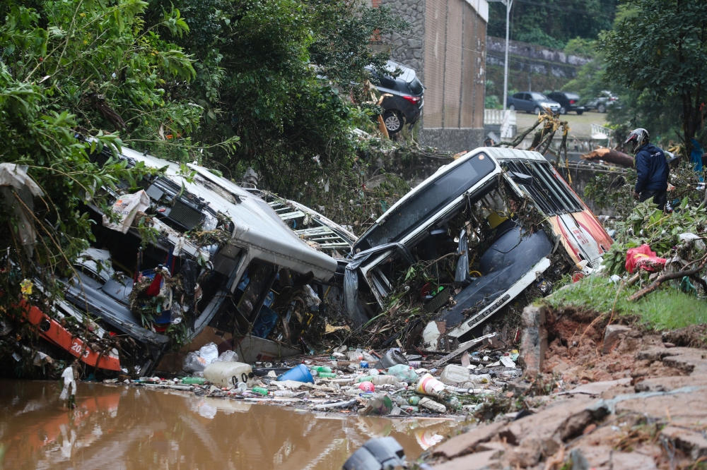 A man observes damaged public buses at a river after pouring rains in Petropolis, Brazil, February 16, 2022. REUTERS/Ricardo Moraes