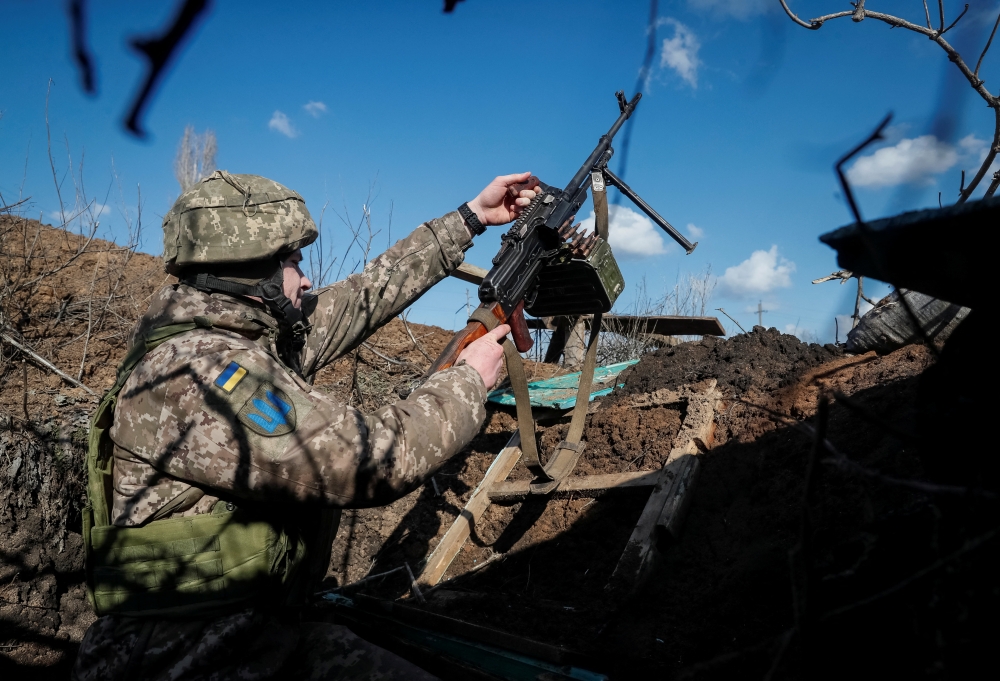 A Ukrainian service member holds a machine gun in a trench at a position on the front line near the village of Travneve in Donetsk region, Ukraine February 21, 2022. Reuters/Gleb Garanich


