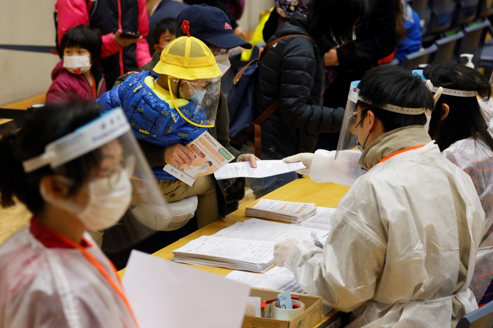 A parent wearing a face mask brings a kid to a community vaccination centre to receive a dose of Sinovac Biotech's CoronaVac COVID-19 vaccine, following the coronavirus disease (COVID-19) outbreak, in Hong Kong, China, February 25, 2022. REUTERS/Tyrone Siu