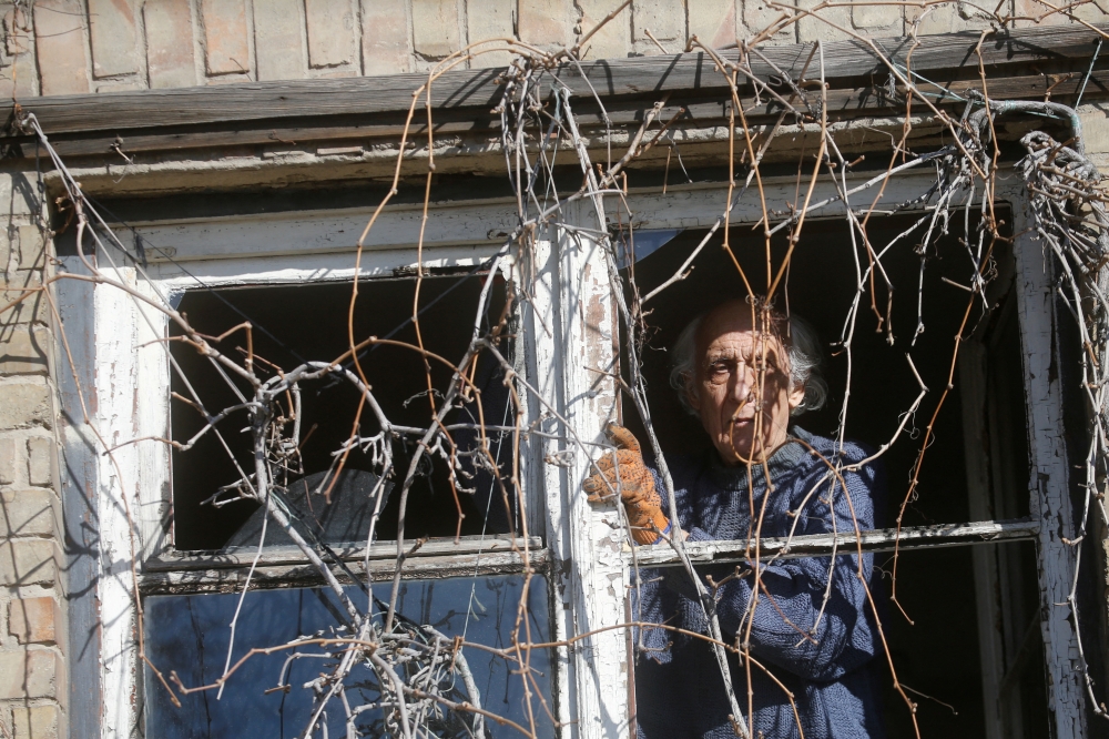 A man inspects a broken window, after Russia launched a massive military operation against Ukraine, in Kyiv, Ukraine February 26, 2022. REUTERS/Valentyn Ogirenko 