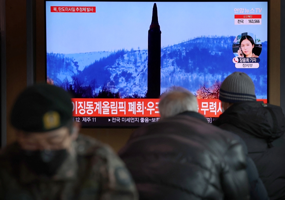 People watch a TV broadcasting file footage of a news report on North Korea firing what appeared to be a ballistic missile, in Seoul, South Korea, February 27, 2022. Yonhap via Reuters
