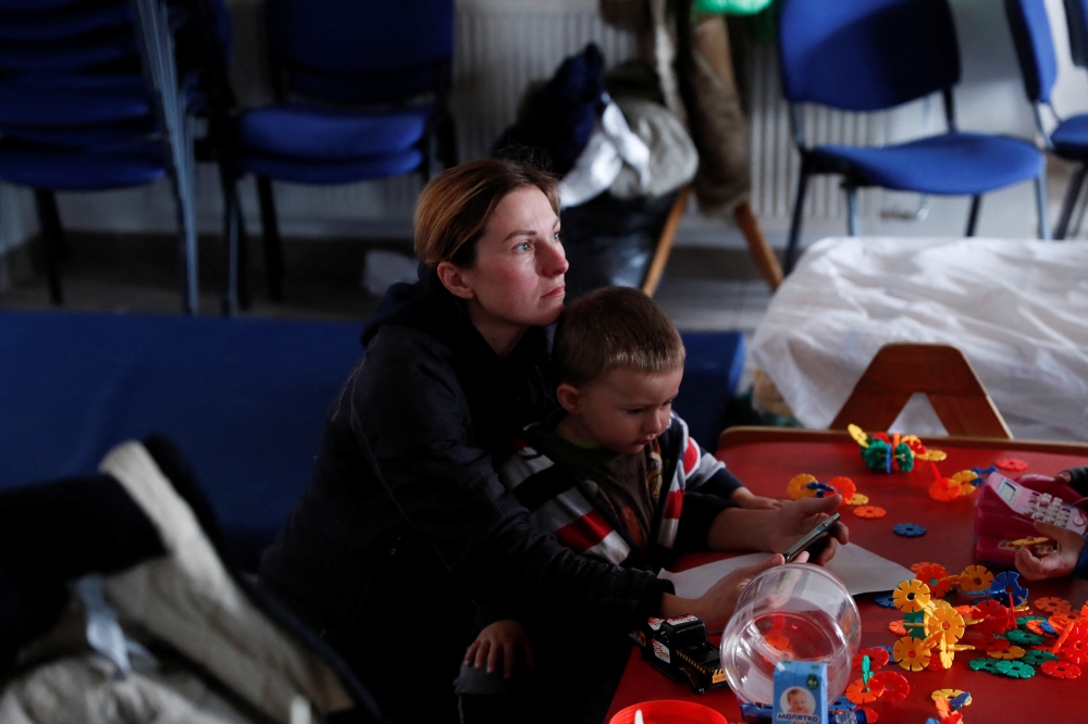 A woman rests with her son after fleeing Russia's invasion of Ukraine, at a refugee shelter in Beregsurany, Hungary, March 5, 2022. Reuters/Bernadett Szabo
 