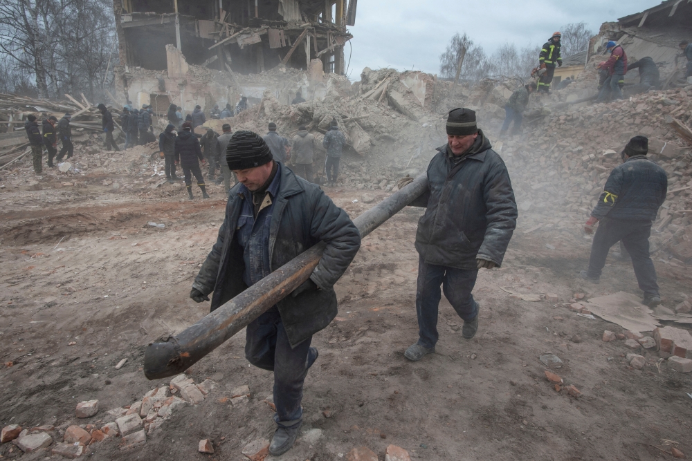 People remove debris at the site of a military base building that, according to the Ukrainian ground forces, was destroyed by an air strike, in the town of Okhtyrka in the Sumy region, Ukraine February 28, 2022. Irina Rybakova/Press service of the Ukrainian ground forces/Handout via Reuters 