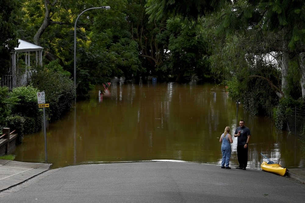 People look on as residential properties and roads are submerged under floodwater in Windsor, north-west of Sydney, Australia, March 9, 2022. AAP Image/Bianca De Marchi via REUTERS