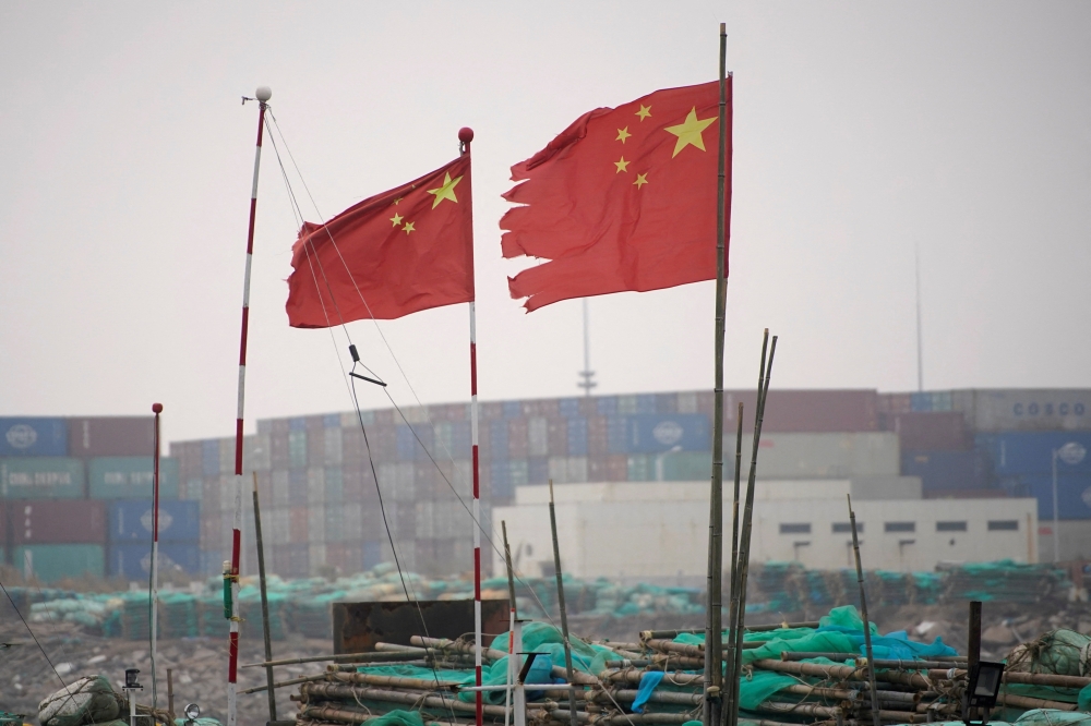 FILE PHOTO: Chinese flags flutter near containers stacked at the Yangshan Deep Water Port in Shanghai, China January 13, 2022. REUTERS/Aly Song