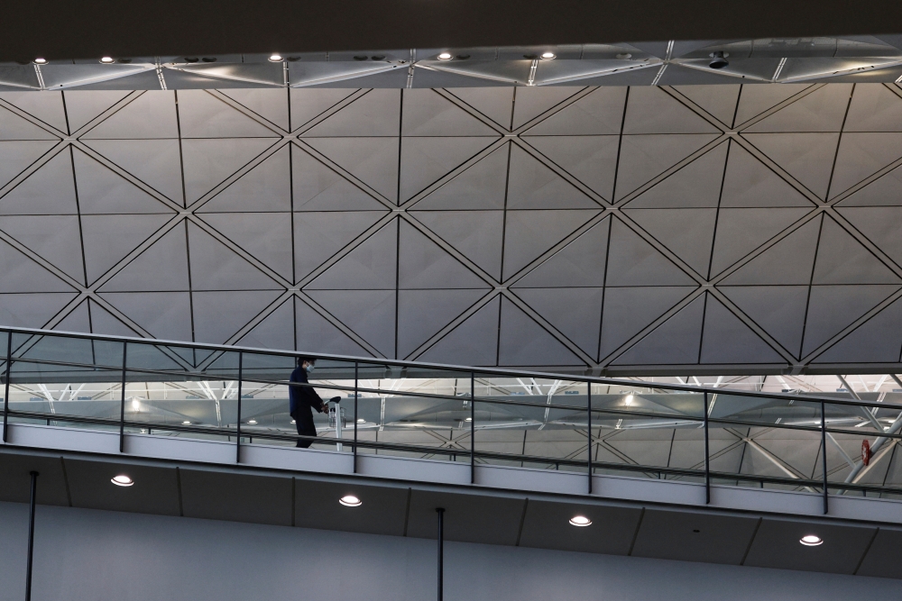 A traveller wearing a protective face mask walks through the Hong Kong International Airport during the coronavirus disease (COVID-19) pandemic in Hong Kong, China, March 17, 2022. REUTERS/Tyrone Siu
