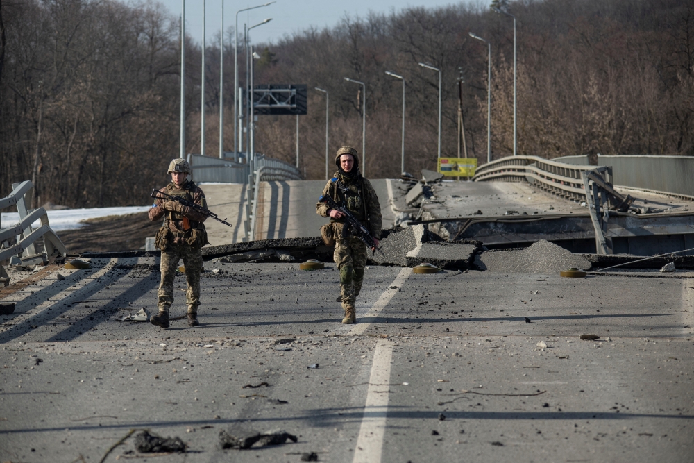 Ukrainian service members walk next to a destroyed bridge between the towns of Trostianets and Okhtyrka amid Russia's attack on Ukraine continues, in the Sumy region, Ukraine March 19, 2022. Iryna Rybakova/Press service of the Ukrainian Ground Forces/Handout via REUTERS