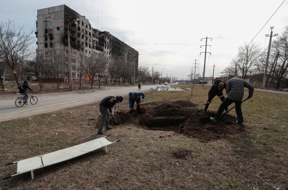 People dig a grave for victims killed during Ukraine-Russia conflict in a street in the besieged southern port city of Mariupol, Ukraine March 20, 2022. REUTERS/Alexander Ermochenko