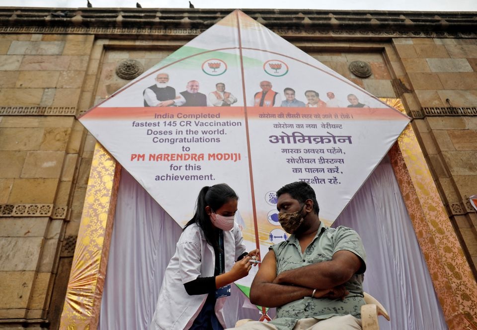 A man receives a dose of vaccine against the coronavirus disease (COVID-19) in front of a giant kite, installed to mark administering 1.45 billion coronavirus disease (COVID-19) vaccine doses in India, Ahmedabad, India, January 6, 2022. REUTERS/Amit Dave

