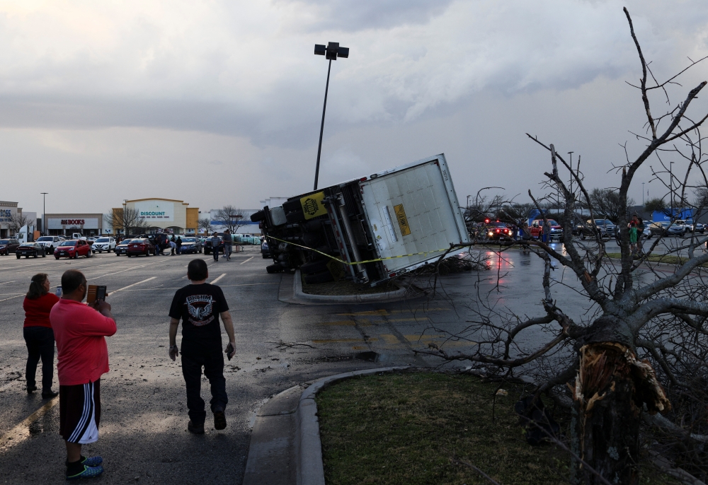 People look at an overturned truck in a parking lot after a tornado in a widespread storm system touched down in Round Rock, Texas, U.S., March 21, 2022. REUTERS/Tamir Kalifa