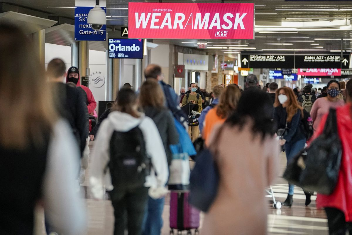 Travelers are seen under a PSA advising mask wearing in a concourse during the holiday season as the coronavirus Omicron variant threatens to increase case numbers at Hartsfield-Jackson Atlanta International Airport in Atlanta, Georgia, U.S. December 22, 2021. REUTERS/Elijah Nouvelage

