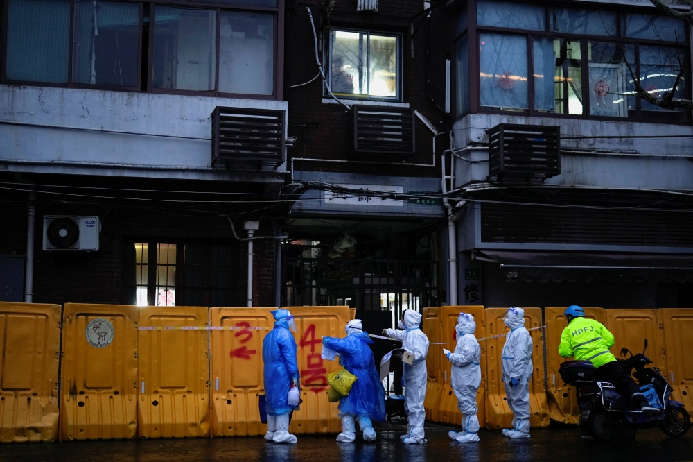 Medical staff in personal protective equipment (PPE) work in front of barriers of an area under lockdown, amid the coronavirus disease (COVID-19) pandemic, in Shanghai, China March 25, 2022. REUTERS/Aly Song