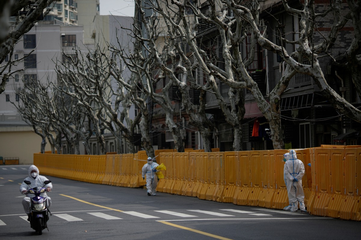 Staff in personal protective equipment (PPE) work by a barrier of an area under lockdown amid the coronavirus disease (COVID-19) pandemic, in Shanghai, China March 26, 2022. REUTERS/Aly Song
