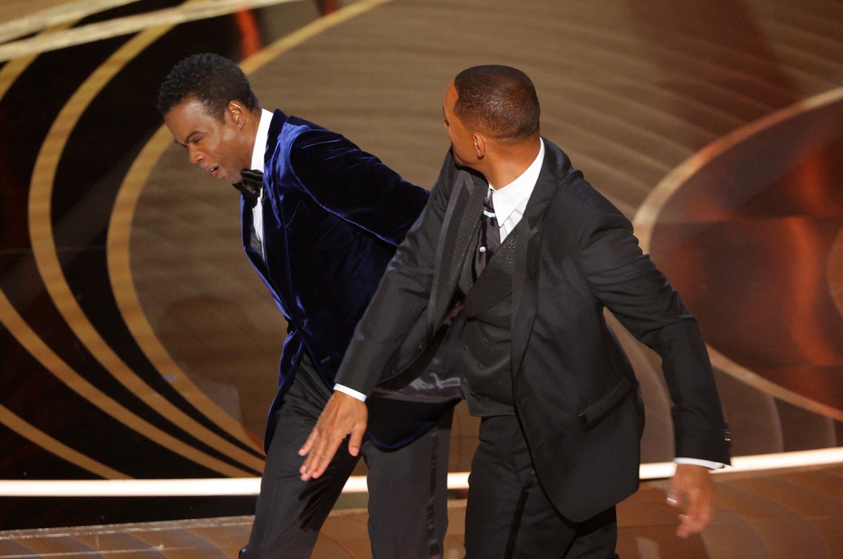 Will Smith (R) hits Chris Rock as Rock spoke on stage during the 94th Academy Awards in Hollywood, Los Angeles, California, U.S., March 27, 2022. REUTERS/Brian Snyder