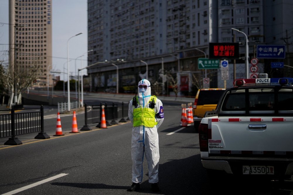 A police officer in a protective suit keeps watch near a bridge leading to the Pudong area across the Huangpu river, after traffic restrictions amid the lockdown to contain the spread of the coronavirus disease (COVID-19) in Shanghai, China March 28, 2022. REUTERS/Aly Song