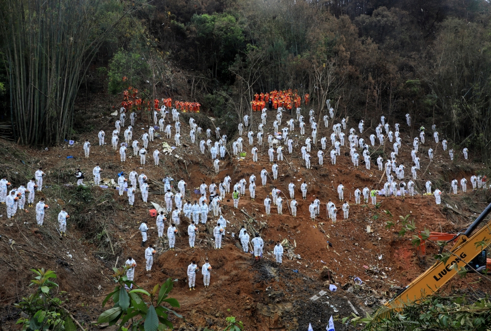 Rescue workers stand in a silent tribute at the site to mourn the victims of a China Eastern Airlines Boeing 737-800 plane, flight MU5735, that crashed in Wuzhou, Guangxi Zhuang Autonomous Region, China, March 27, 2022. Picture taken March 27, 2022. cnsphoto via REUTERS