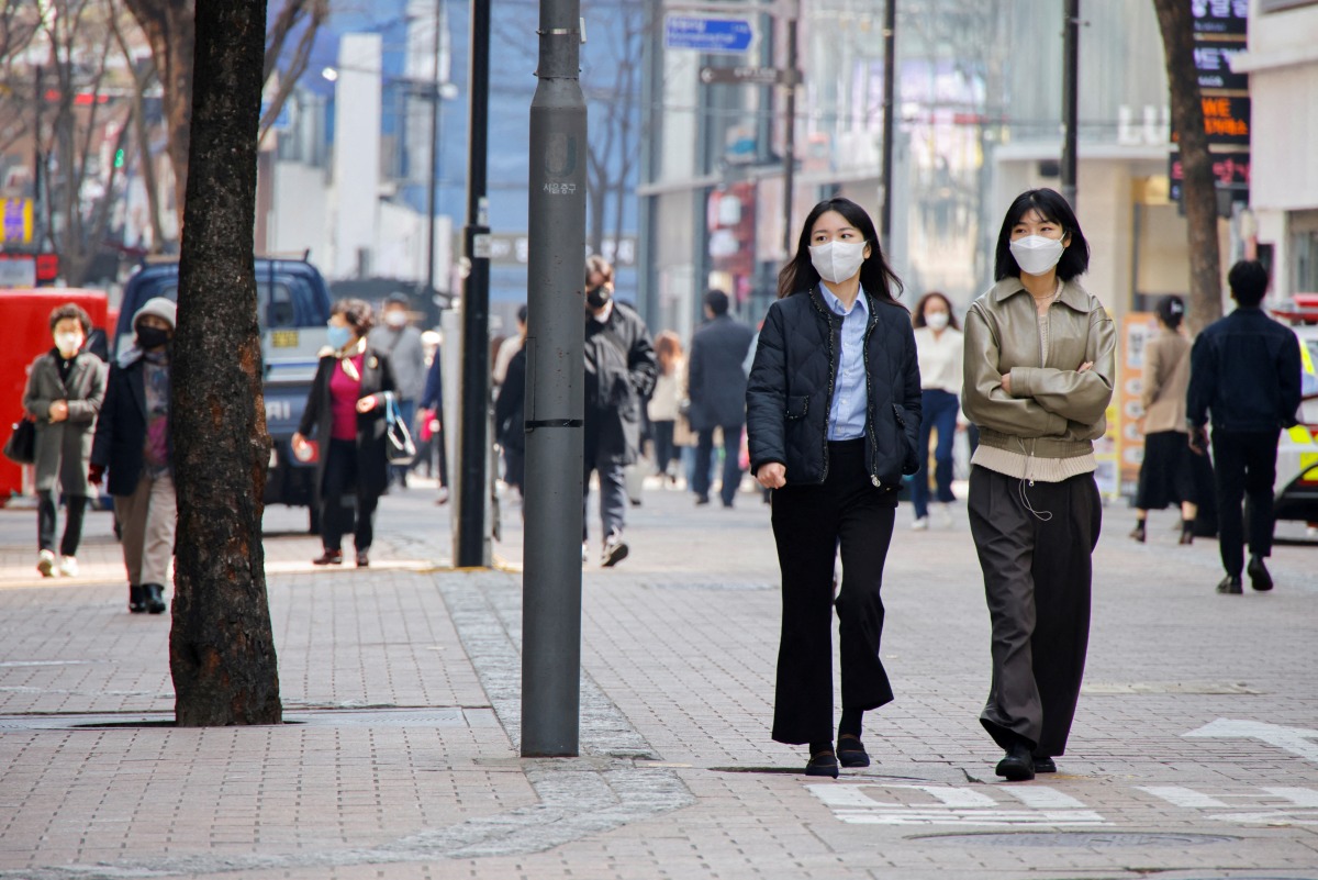FILE PHOTO: Women wearing masks walk in a shopping district amid the coronavirus disease (COVID-19) pandemic in SEOUL, South Korea, March 16, 2022. REUTERS/Heo Ran/File Photo

