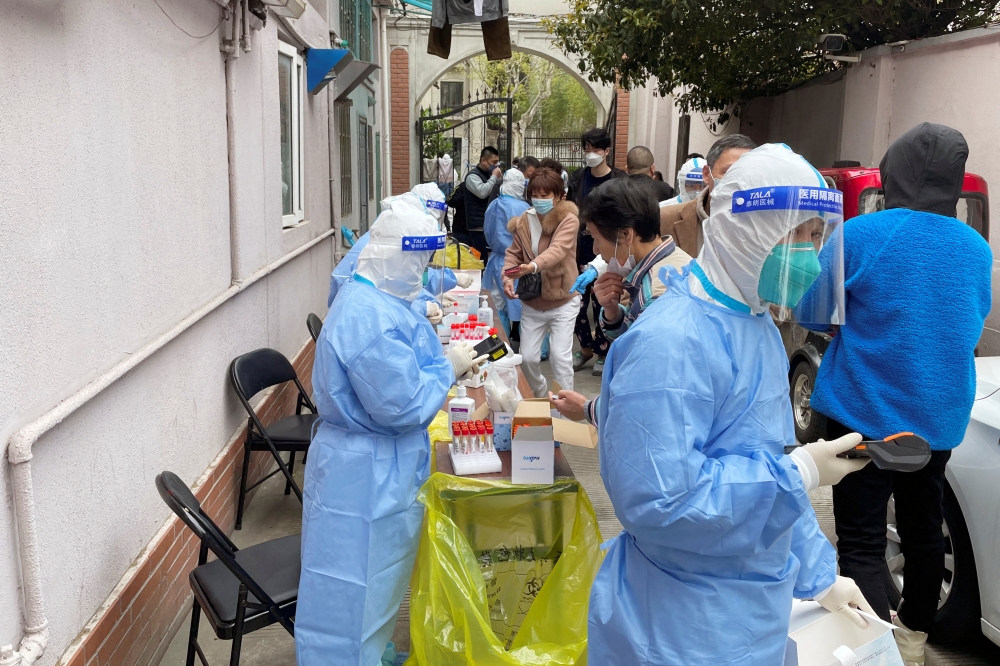 Medical workers in protective suits administer nucleic acid testing for residents in a residential compound in Shanghai, China April 1, 2022. Reuters/Brenda Goh