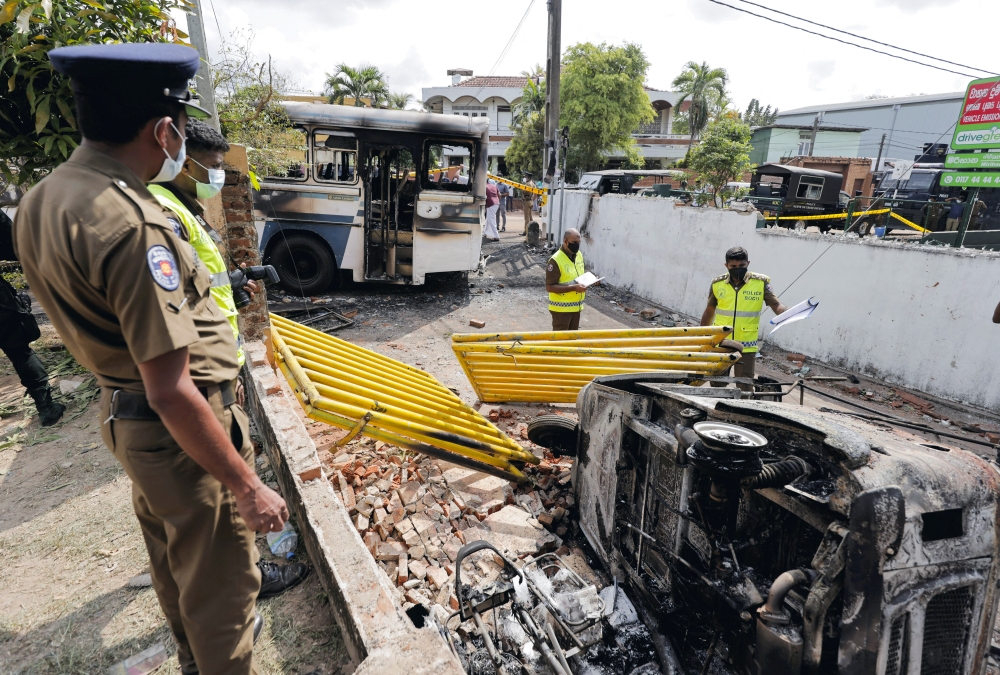 Sri Lankan crime scene officers inspect damaged vehicles after they were set on fire by demonstrators at the top of the road to Sri Lankan President Gotabaya Rajapaksa's residence during a protest against him in Colombo, Sri Lanka April 1, 2022. Reuters/Dinuka Liyanawatte
