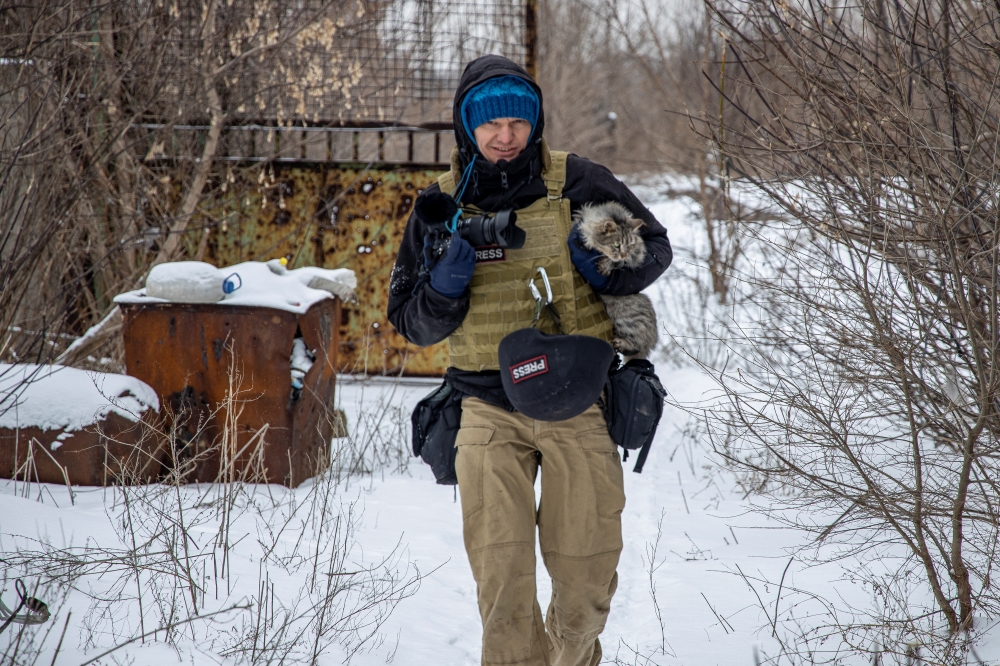 Ukrainian photographer Maksim Levin carries a cat near the line of separation from Russian-backed separatists in Donetsk region, Ukraine January 25, 2022. Picture taken January 25, 2022. REUTERS/Stanislav Kozliuk