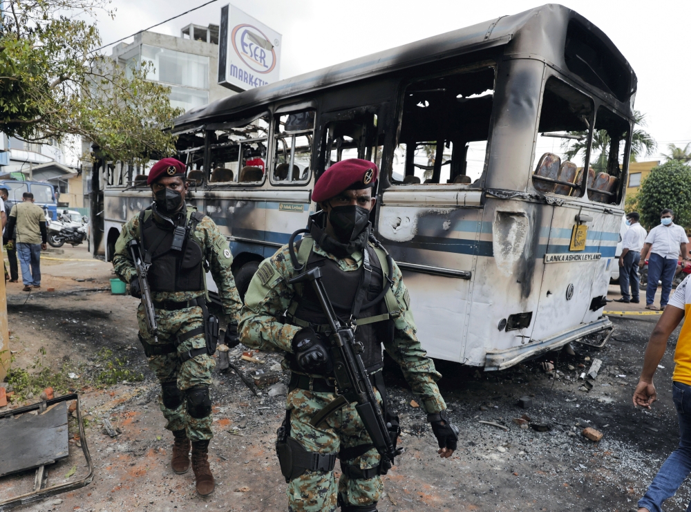 ri Lankan army commandos walk past a damaged bus after it was set on fire by demonstrators at the top of the road to Sri Lankan President Gotabaya Rajapaksa's residence during a protest against him, as many parts of the crisis-hit country face up to 13 hours without electricity due to a shortage of foreign currency to import fuel, in Colombo, Sri Lanka April 1, 2022. REUTERS/Dinuka Liyanawatte