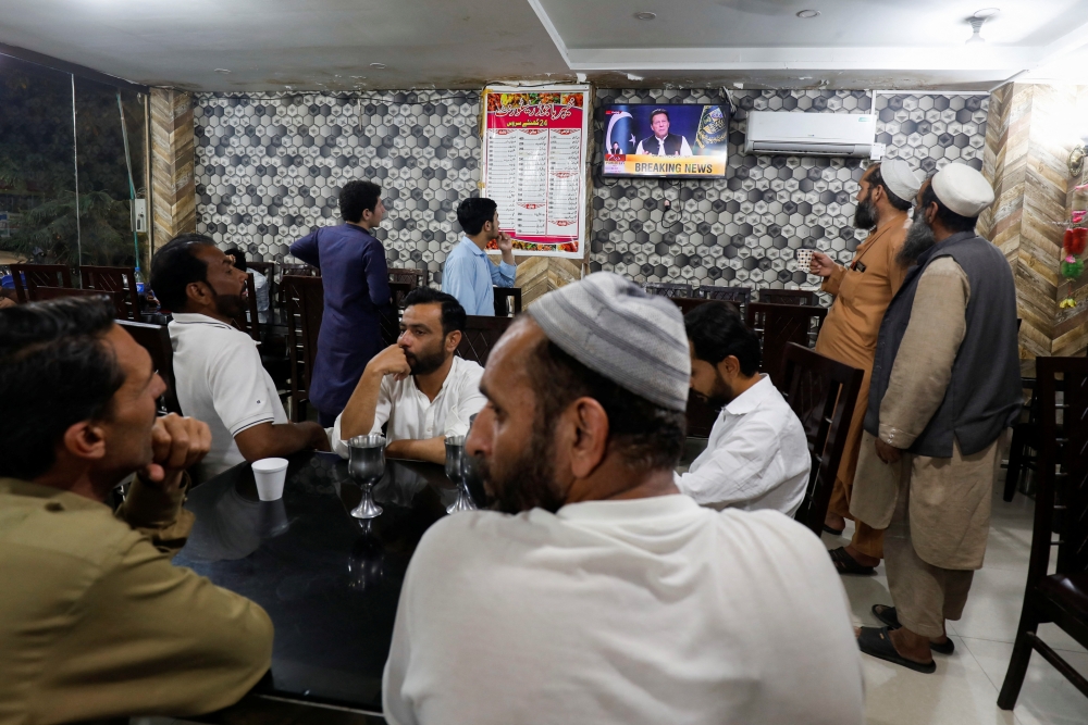 People watch the speech of Pakistani Prime Minister Imran Khan on a television screen, at a cafe in Islamabad, Pakistan, April 8, 2022. Reuters/Akhtar Soomro
 