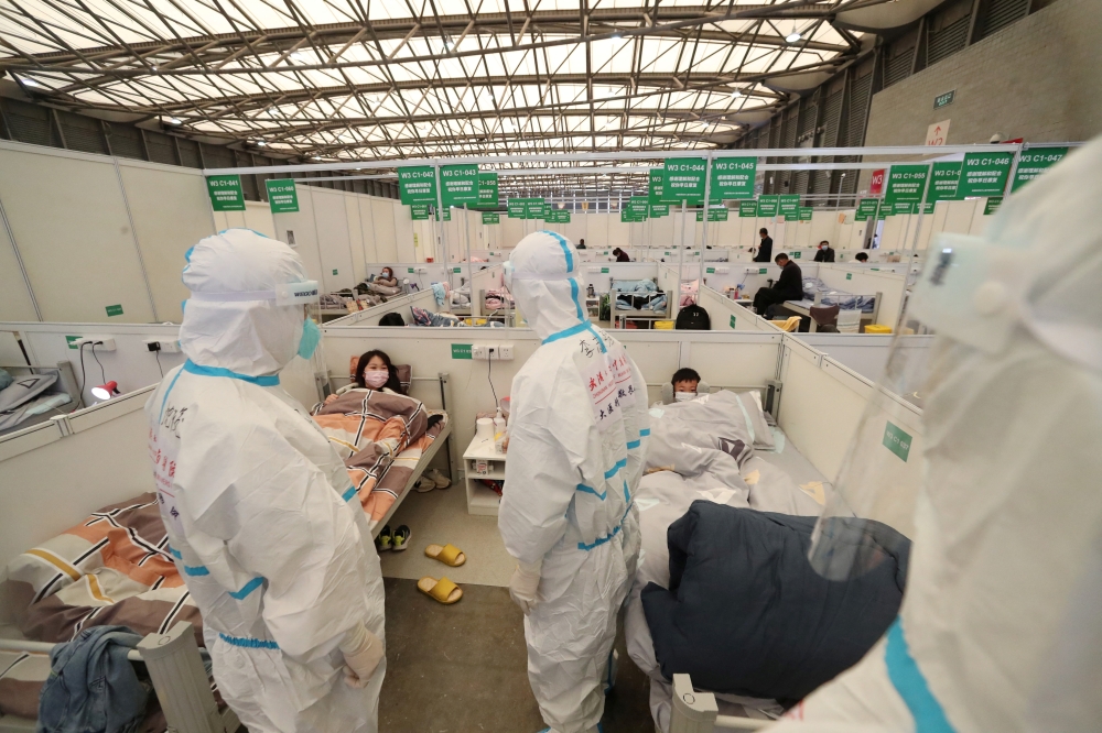 Medical workers in protective suits conduct ward rounds at Shanghai New International Exhibition Hall, which has been turned into a makeshift hospital for the coronavirus disease (COVID-19) patients, April 9, 2022. China Daily via Reuters 